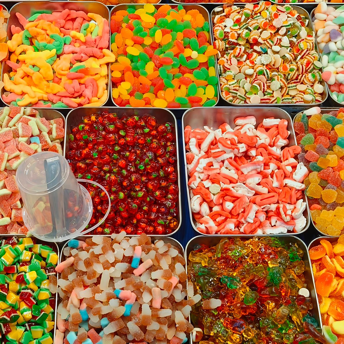 Vibrant assortments of colorful candies presented in metal trays for sale.