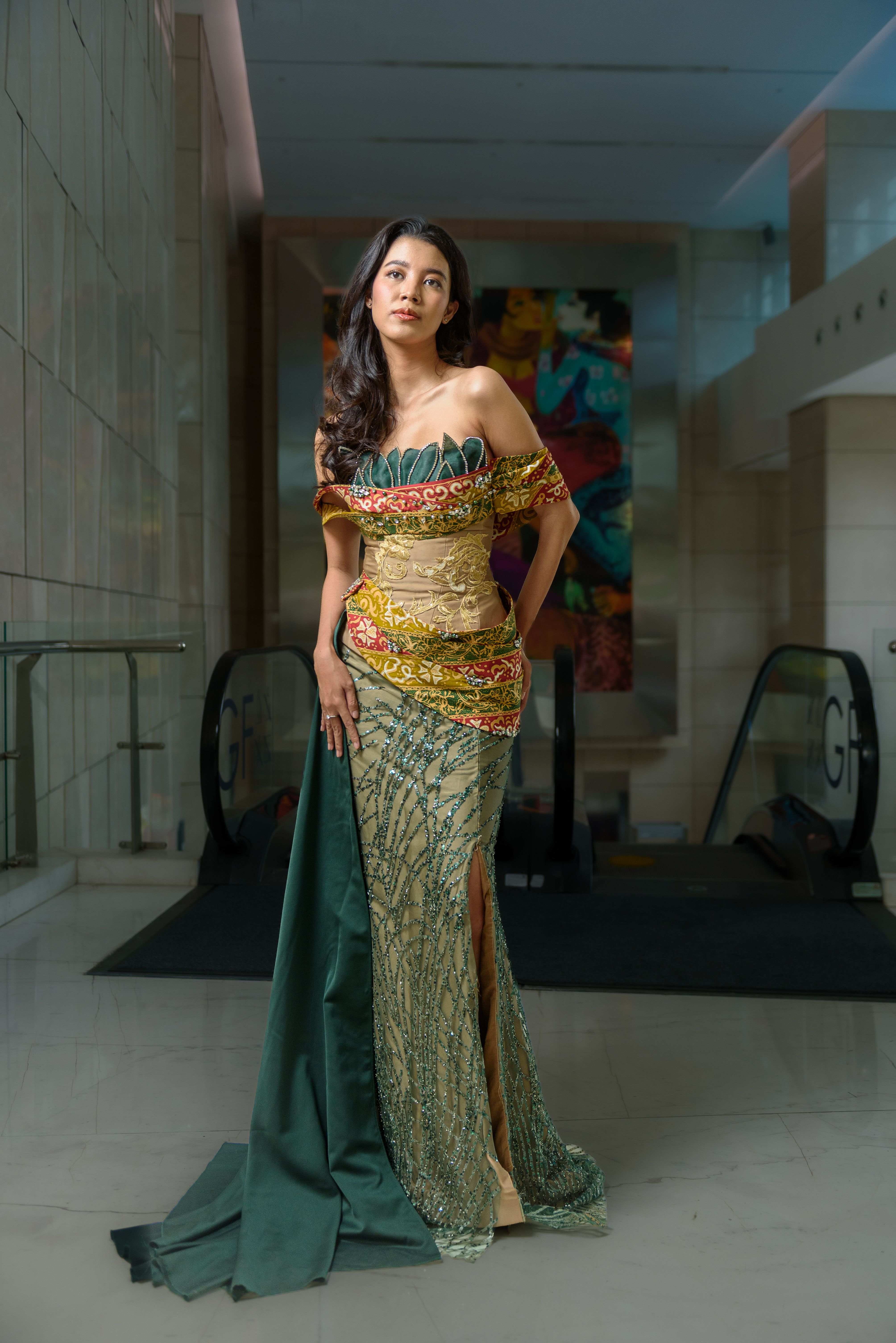 Elegant woman in colorful traditional dress in a modern Jakarta indoor setting.