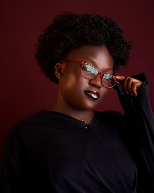 Free Confident woman in red glasses and black attire on dark background. Stock Photo