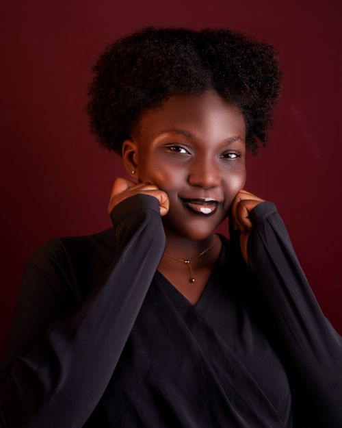 Free Portrait of a smiling woman with curly hair against a maroon background, exuding confidence. Stock Photo