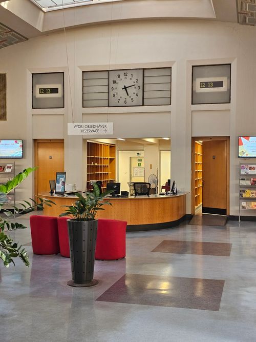 Free Modern library interior in Prague with a central desk and large wall clock. Bright and welcoming. Stock Photo