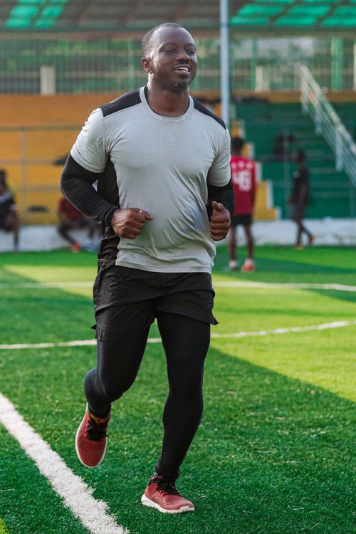 Free A man jogging on an outdoor sports field during the day, focusing on fitness and healthy lifestyle. Stock Photo