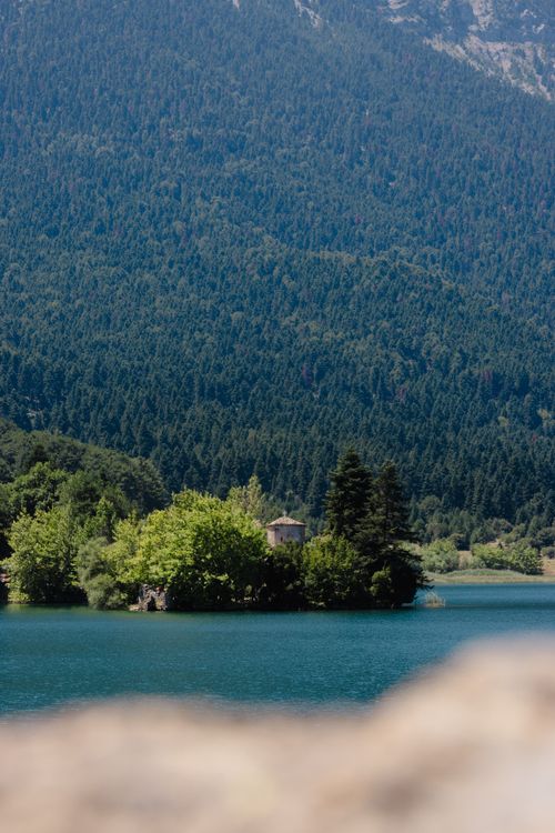 Free Tranquil scene of Lake Doxa surrounded by lush forest and mountains, Greece. Stock Photo