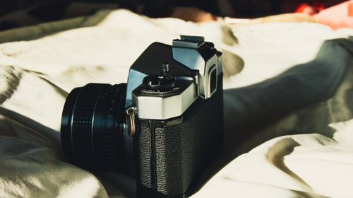 Free A close-up of a vintage film camera resting on a sunlit bed, evoking nostalgia. Stock Photo