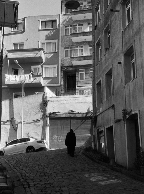 Free A person walks down a cobblestone street in Istanbul, surrounded by residential buildings. Stock Photo