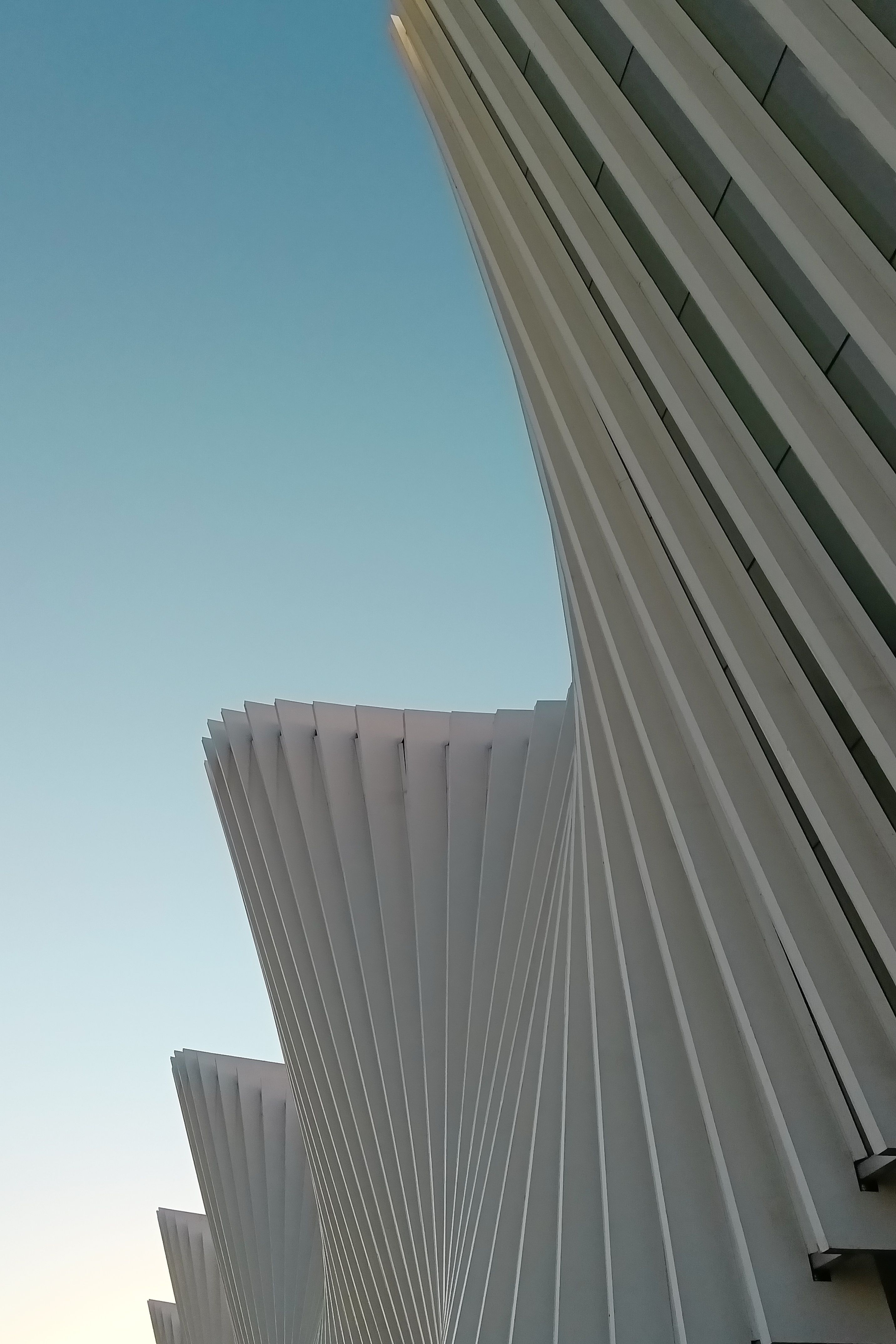 Elegant modern architecture with white geometric curves against blue sky.