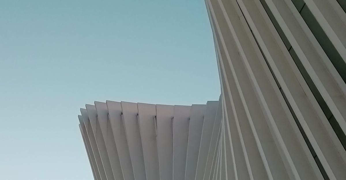 Elegant modern architecture with white geometric curves against blue sky.