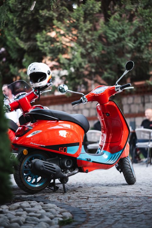 Free Bright orange scooter parked on cobblestone street in Eskişehir, Türkiye, showcasing urban lifestyle and vibrant design. Stock Photo