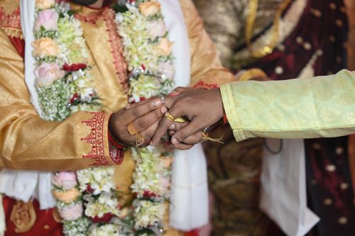 Free A groom and bride exchanging rings during a traditional Indian wedding ceremony, adorned with floral garlands. Stock Photo