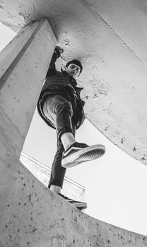 Black and white photo of a man in trendy attire, seen from a low angle.