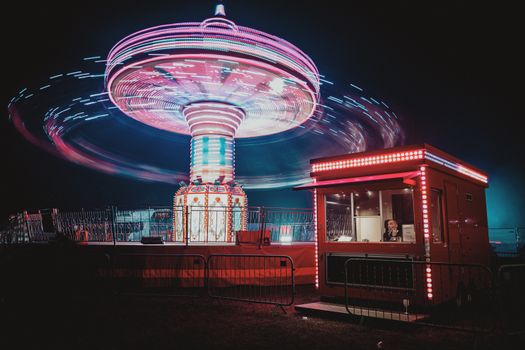 Vibrant image of a spinning fairground ride with neon lights at night.
