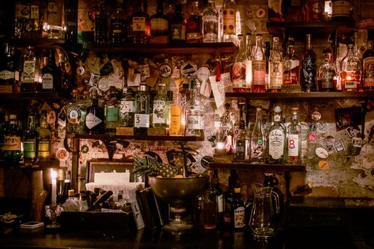 A dimly lit bar with various liquor bottles and unique decor creates a warm atmosphere.