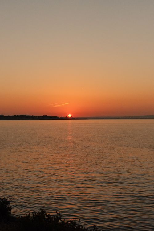 Free Peaceful sunset view over still ocean waters, perfect for relaxation and tranquility themes. Stock Photo