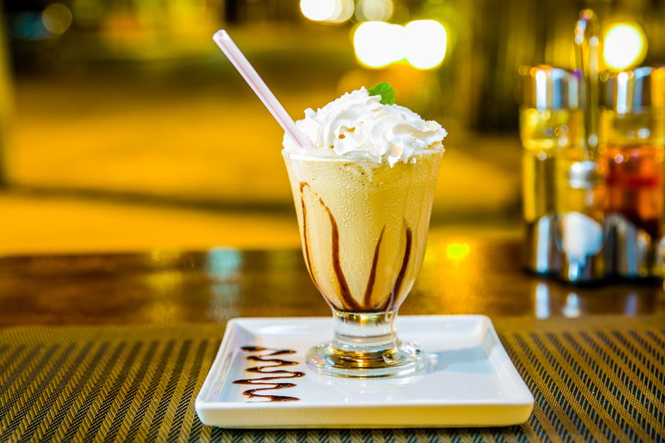 A creamy milkshake with chocolate drizzle, topped with whipped cream, perfect for a refreshing dessert.