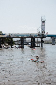 A woman paddles on a river near a bridge in Chattanooga, Tennessee, during a sunny day.