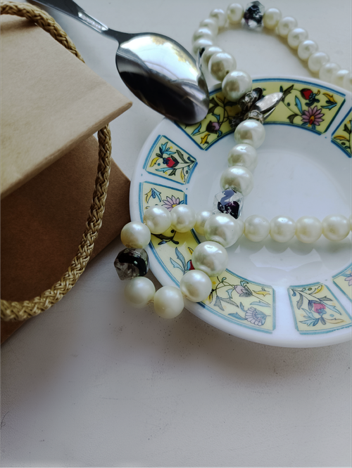Free Pearl necklace displayed on a decorative plate with shopping bag. Stock Photo