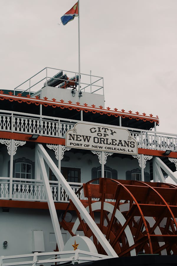 Contemporary steamboat painted in red and white colors with side wheel and signboard with inscription city of New Orleans