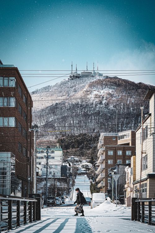無料 澄み渡る空の下、背景に函館山を望む、雪に覆われた日本の函館の街並み。 写真素材