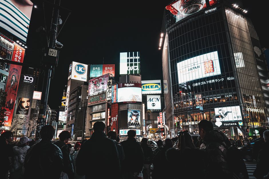 東京・渋谷スクランブル交差点の活気あふれる夜景。賑やかな人々やまばゆいネオンサインが印象的だ。