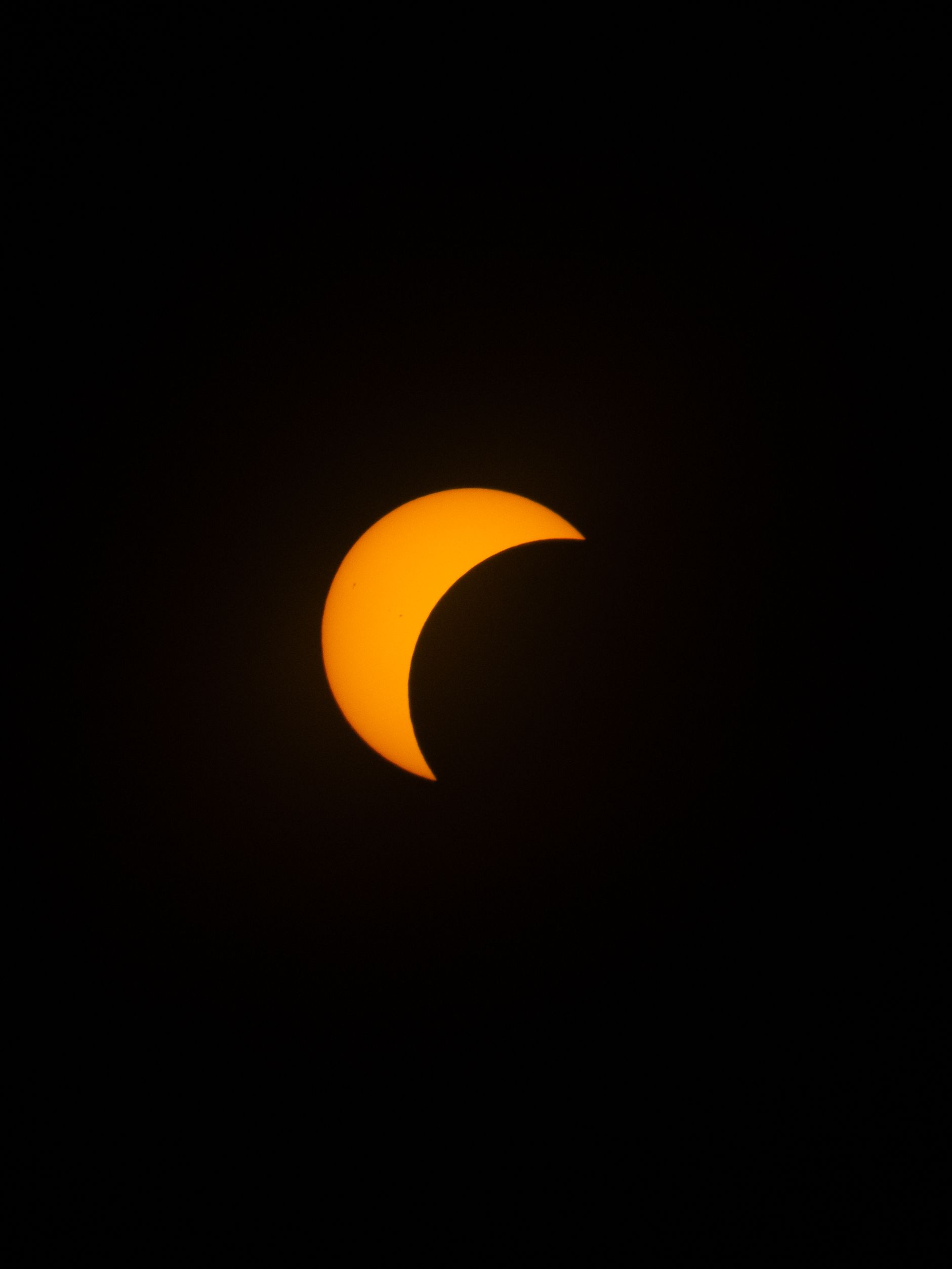 Fotomural Un primer plano cautivador de un eclipse solar, que destaca la media luna que se pone sobre un fondo oscuro.