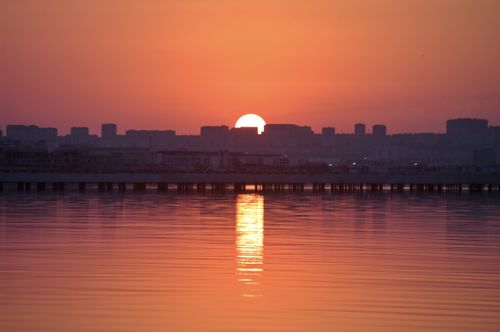 Free A stunning sunset over Baku's skyline with reflections on the Caspian Sea, capturing the vibrant cityscape in warm hues. Stock Photo