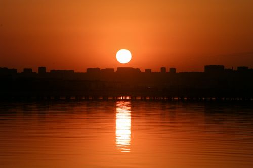 Free Silhouetted cityscape of Baku during sunset with reflections on the water. Stock Photo