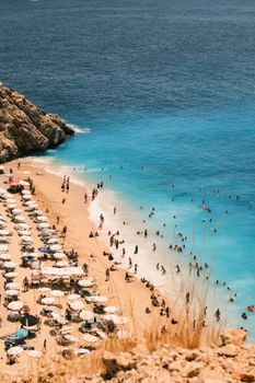 Aerial view of a busy beach with people swimming and sunbathing under umbrellas