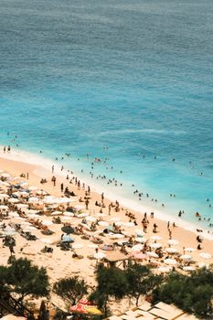 A bustling summer beach scene with people enjoying the ocean and sunbathing.