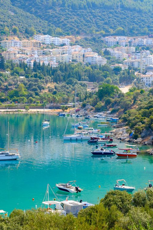 Free A picturesque coastal town with boats docked on turquoise waters under a clear blue sky. Stock Photo