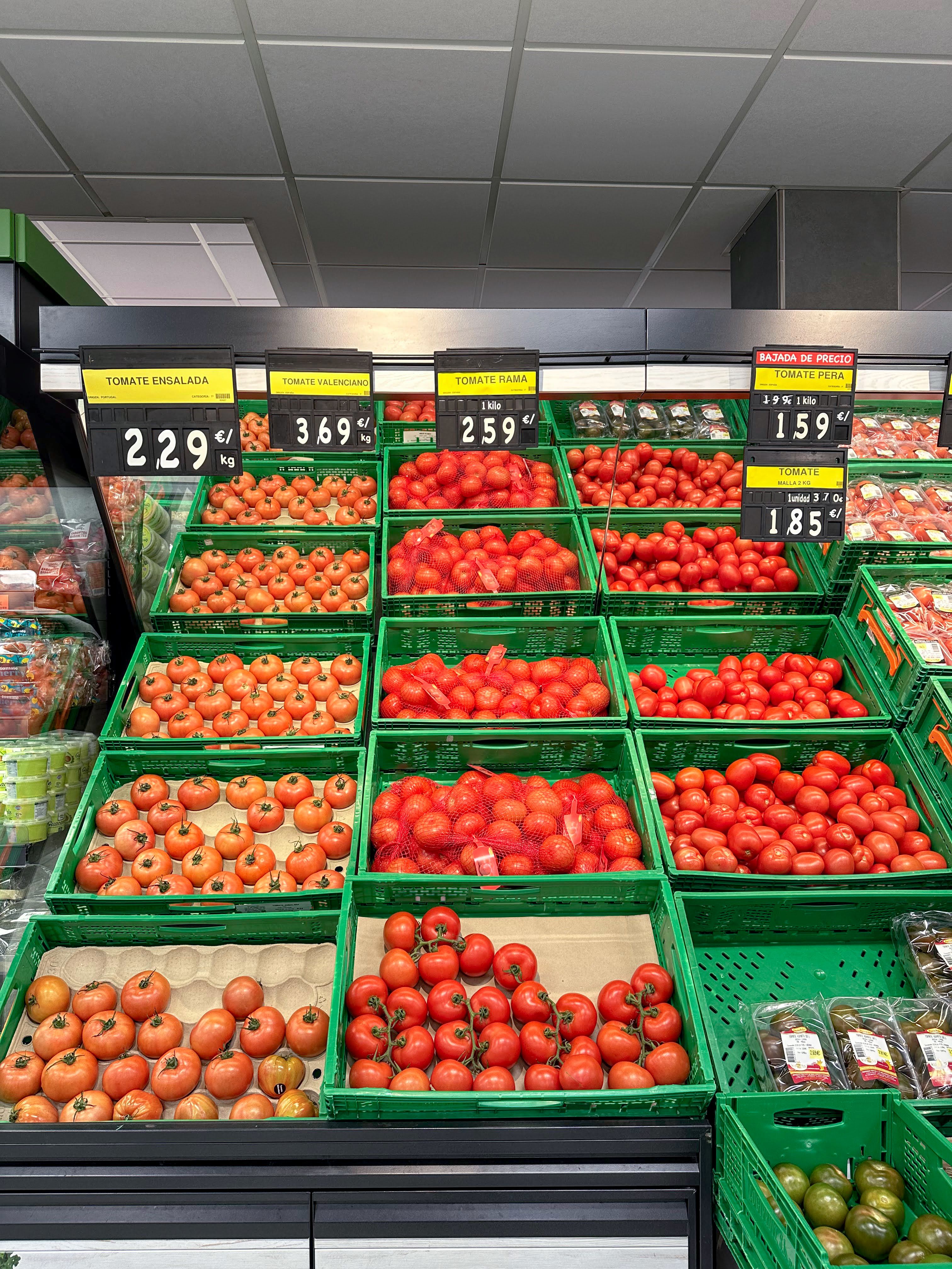 Colorful display of tomatoes in a grocery store with prices shown per kilogram.