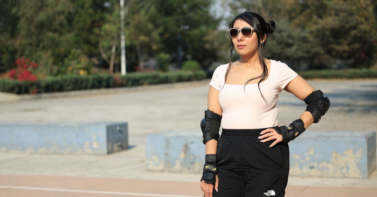 Woman wearing protective gear and sunglasses, enjoying a sunny day outdoors.