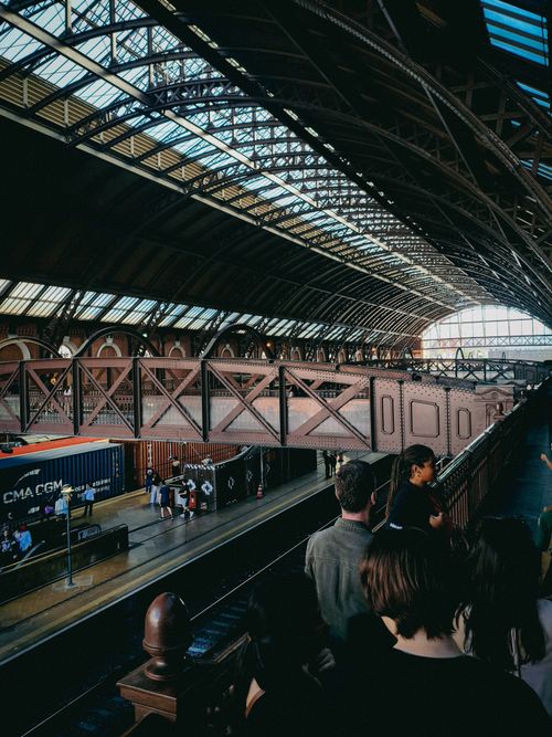 Free A bustling train station with people on the platform and a grand arched roof overhead. Stock Photo