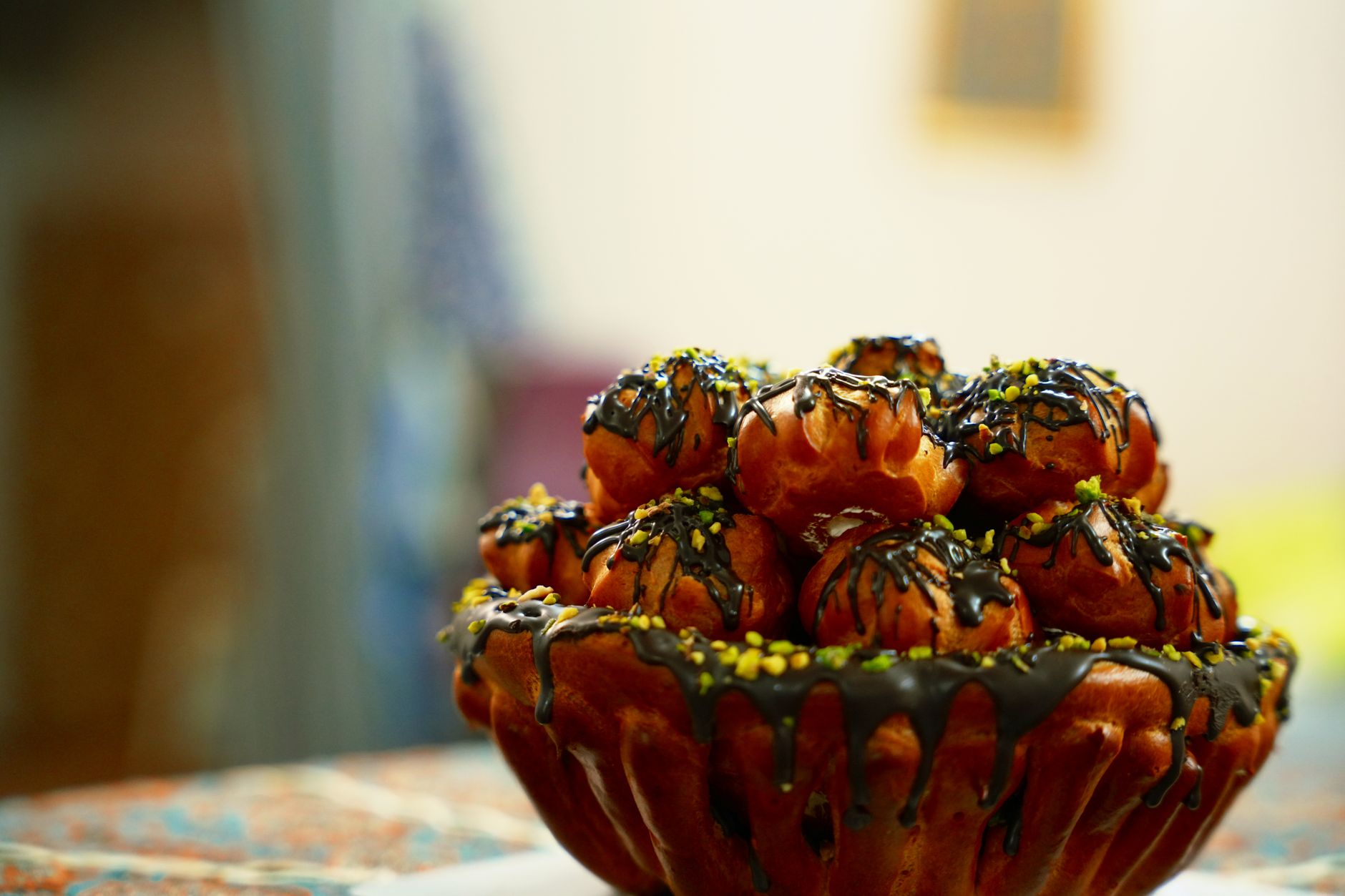 A delicious Persian cream pastry topped with chocolate drizzle and pistachios.