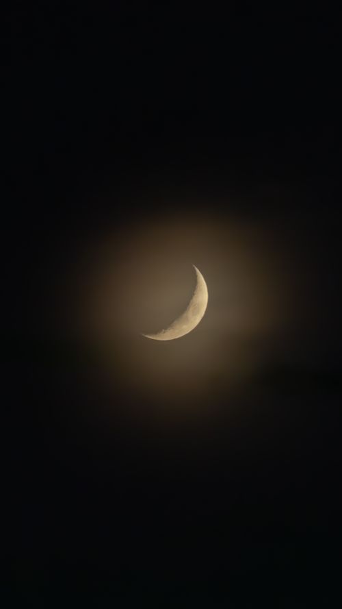 Free A tranquil crescent moon surrounded by a subtle glow in a dark night sky, exemplifying celestial beauty. Stock Photo