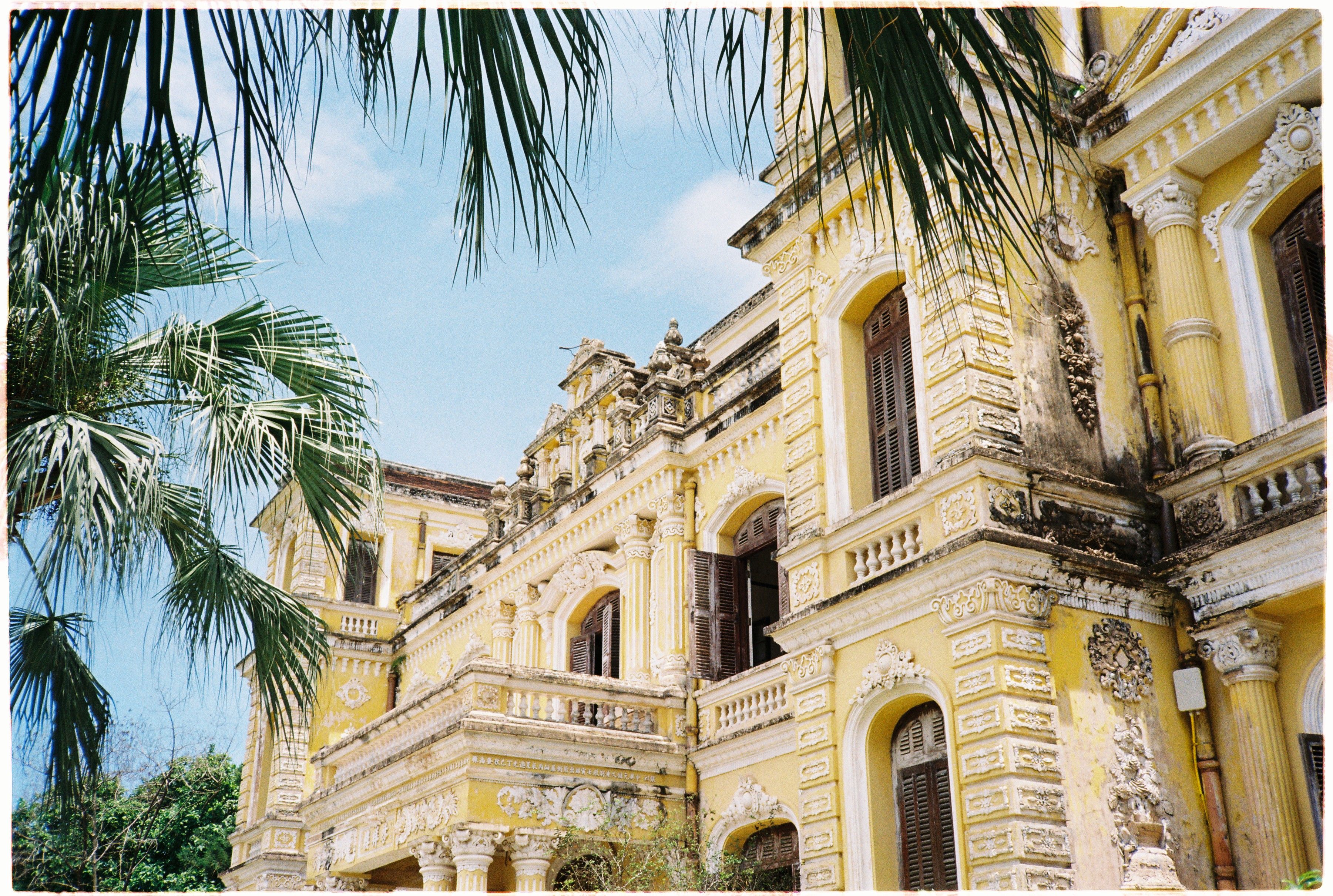 Stunning colonial-era building in Hue, Vietnam, surrounded by palm trees under a clear sky.