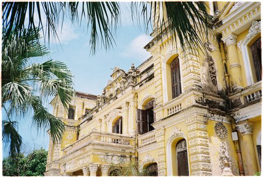 Stunning colonial-era building in Hue, Vietnam, surrounded by palm trees under a clear sky.
