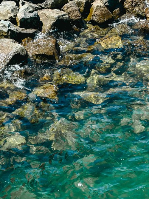 Free Clear turquoise water flows over rocky coastal formations creating a serene and natural scene. Stock Photo
