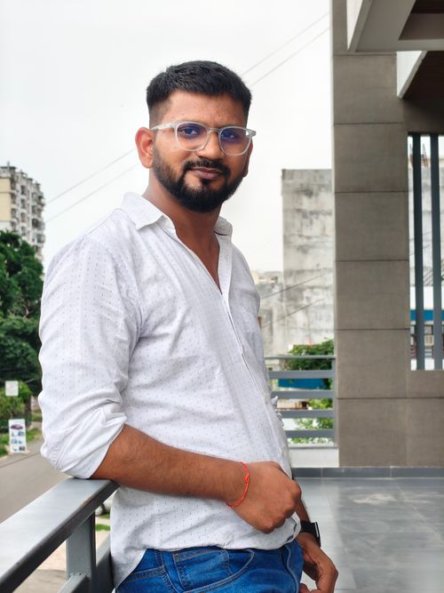 Free Confident young man in casual attire posing outdoors on a city balcony. Stock Photo