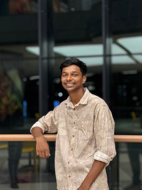 Free Young man smiling indoors, wearing a patterned shirt, conveying a friendly and casual vibe. Stock Photo