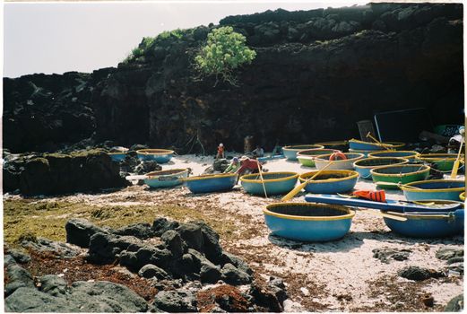Basket boats and rocky shore captured on Ly Son Island, Vietnam. Authentic coastal scene.