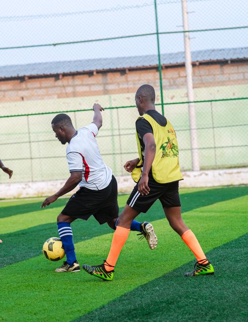 Free Two players engage in a competitive soccer match on a bright green artificial turf field. Stock Photo