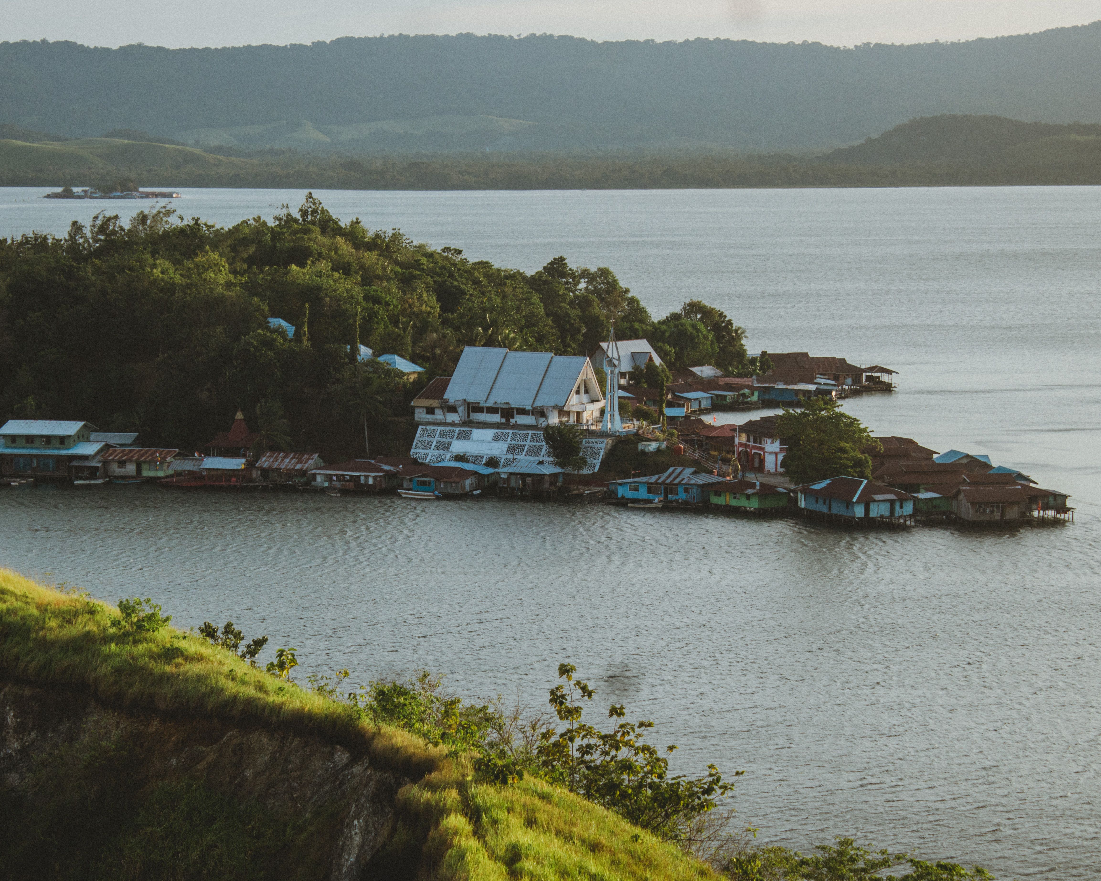Aerial view of Sentani Lake and houses surrounded by lush greenery in Papua, Indonesia.