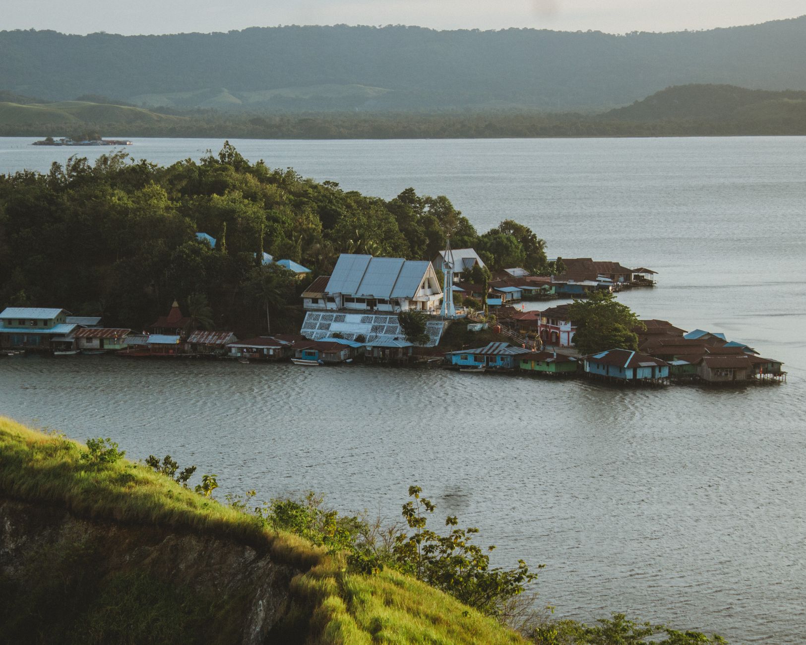 Aerial view of Sentani Lake and houses surrounded by lush greenery in Papua, Indonesia.