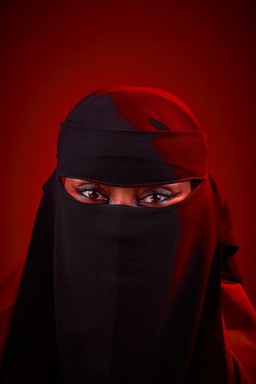 Free Captivating close-up portrait with bold red background and black veil. Stock Photo
