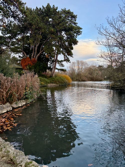 Free Tranquil lake scene with autumnal trees reflecting in the calm waters of an English park. Stock Photo