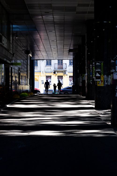 Free A family walks through a shadowed urban passageway, creating dramatic silhouettes. Stock Photo