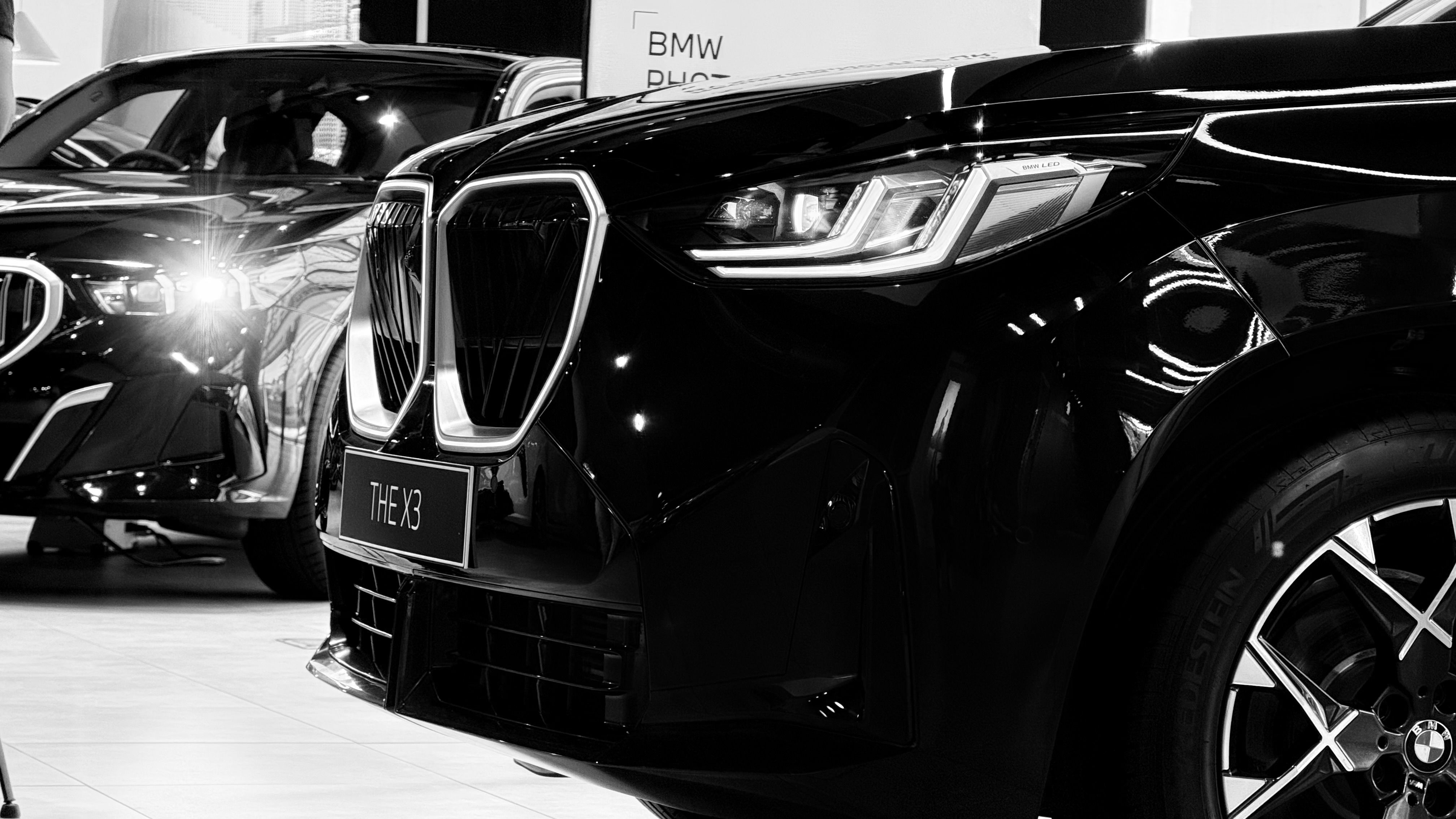 Black and white view of luxury cars in a showroom.