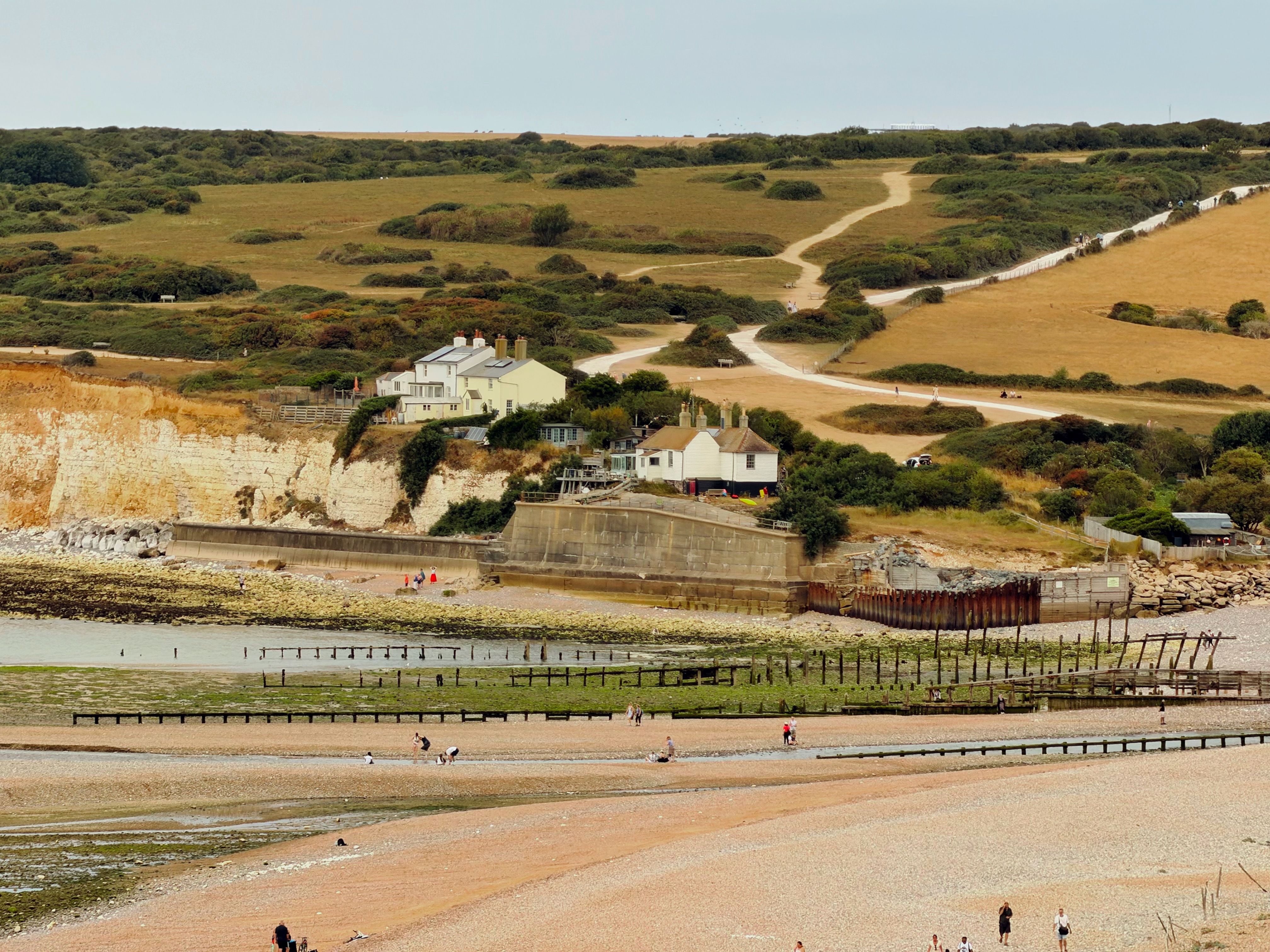 Scenic view of coastal cliffs and path in England with beach goers below.