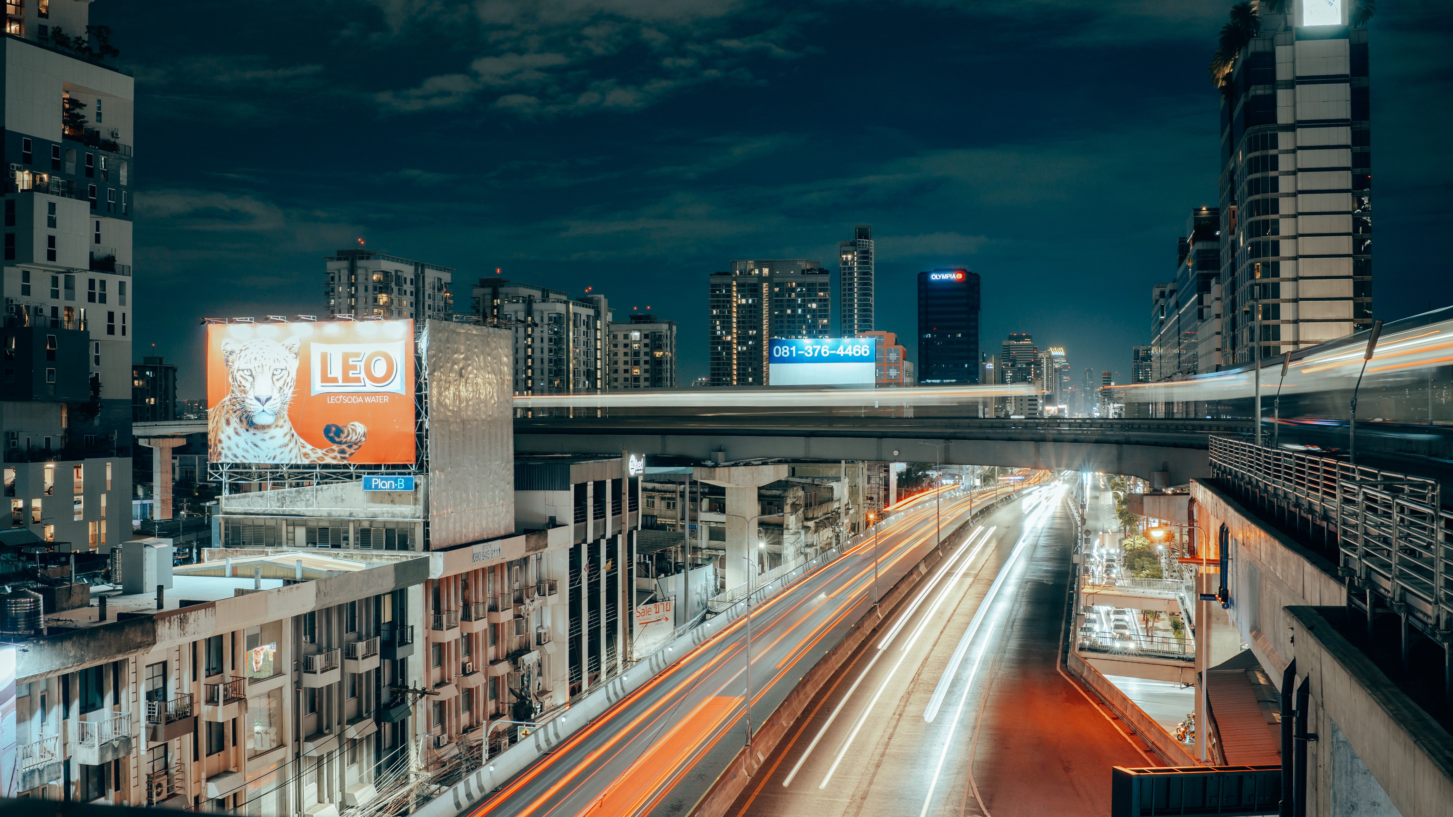 Stunning nighttime view of Bangkok's modern skyline with busy highways and light trails.