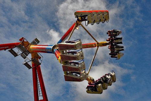 Free Dynamic view of a thrilling amusement park ride set against a clear blue sky. Stock Photo